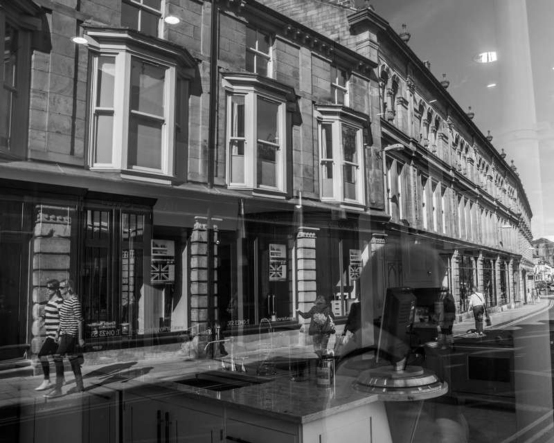 Reflections in a shop window show the buildings on the opposite side of the street.