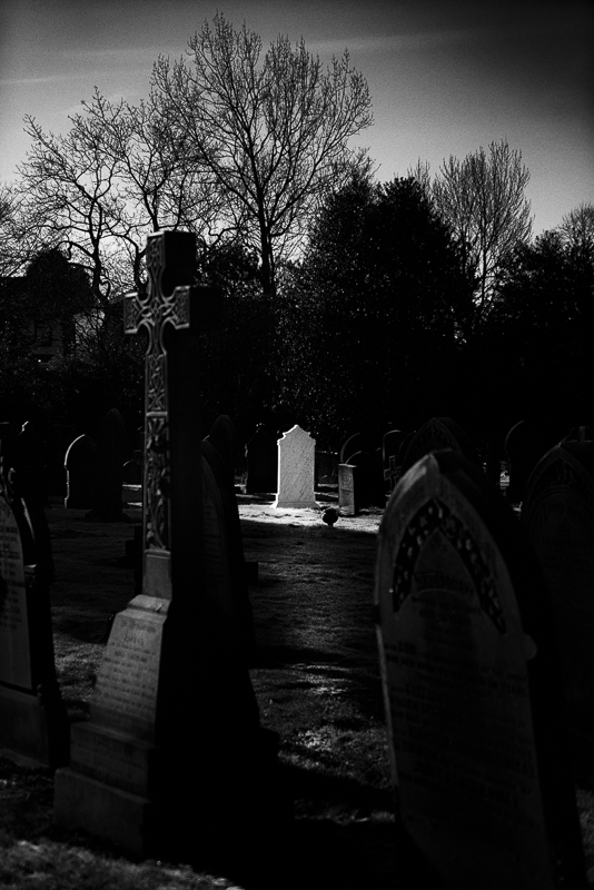 Sun light illuminating a white headstone.